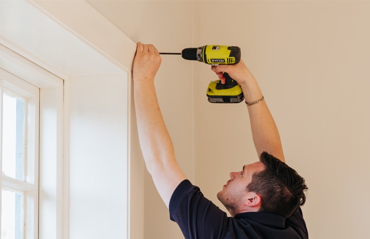 Russells installer installing blind with drill on window frame