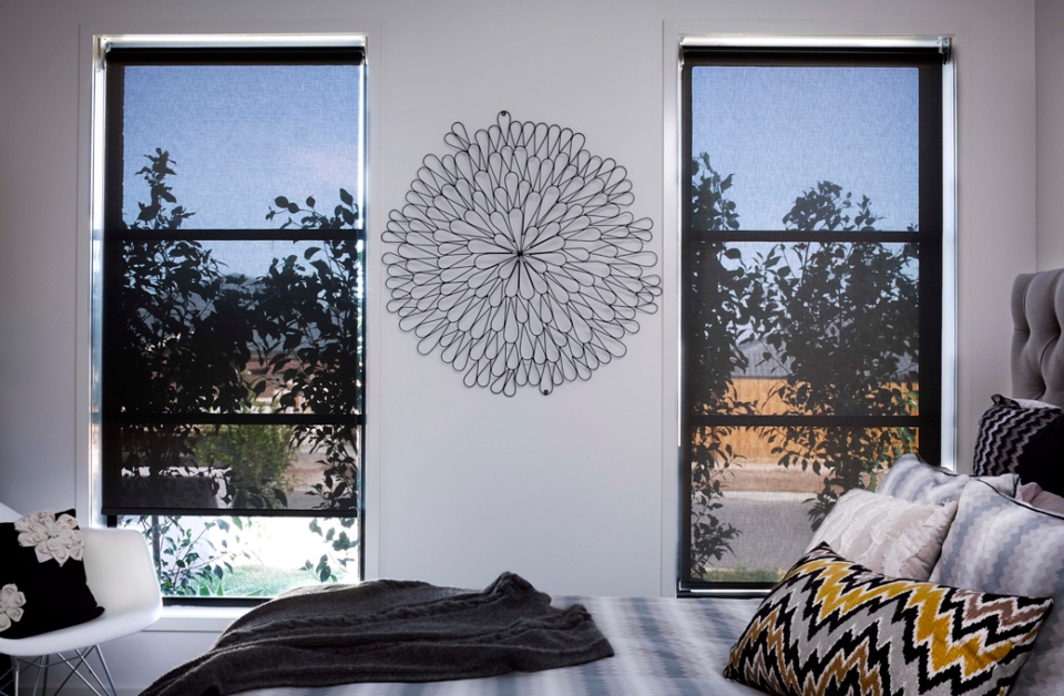 Bedroom with bed and two skinny windows with Russells Roller Sunscreen blinds Black